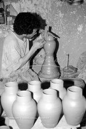 Image du Maroc Professionnelle de  Comme Safi est le chef-lieu de la poterie céramique marocaine, c’est à l’intérieur de son atelier que l’artisan tourneur travaille l'argile brute puis le transforme ainsi dans sa forme, souvent il s'agit d'objets de forme essentielle destinés à l'usage domestique. Quand l’objet est façonné selon le besoin une petit lame est utilisé pour donner à l'objet un aspect lisse. Souvent les artisans ont recours à leur dextérité afin de fignoler la décoration à Safi Vendredi 29 Août 1997.(Photo / Abdeljalil Bounhar)